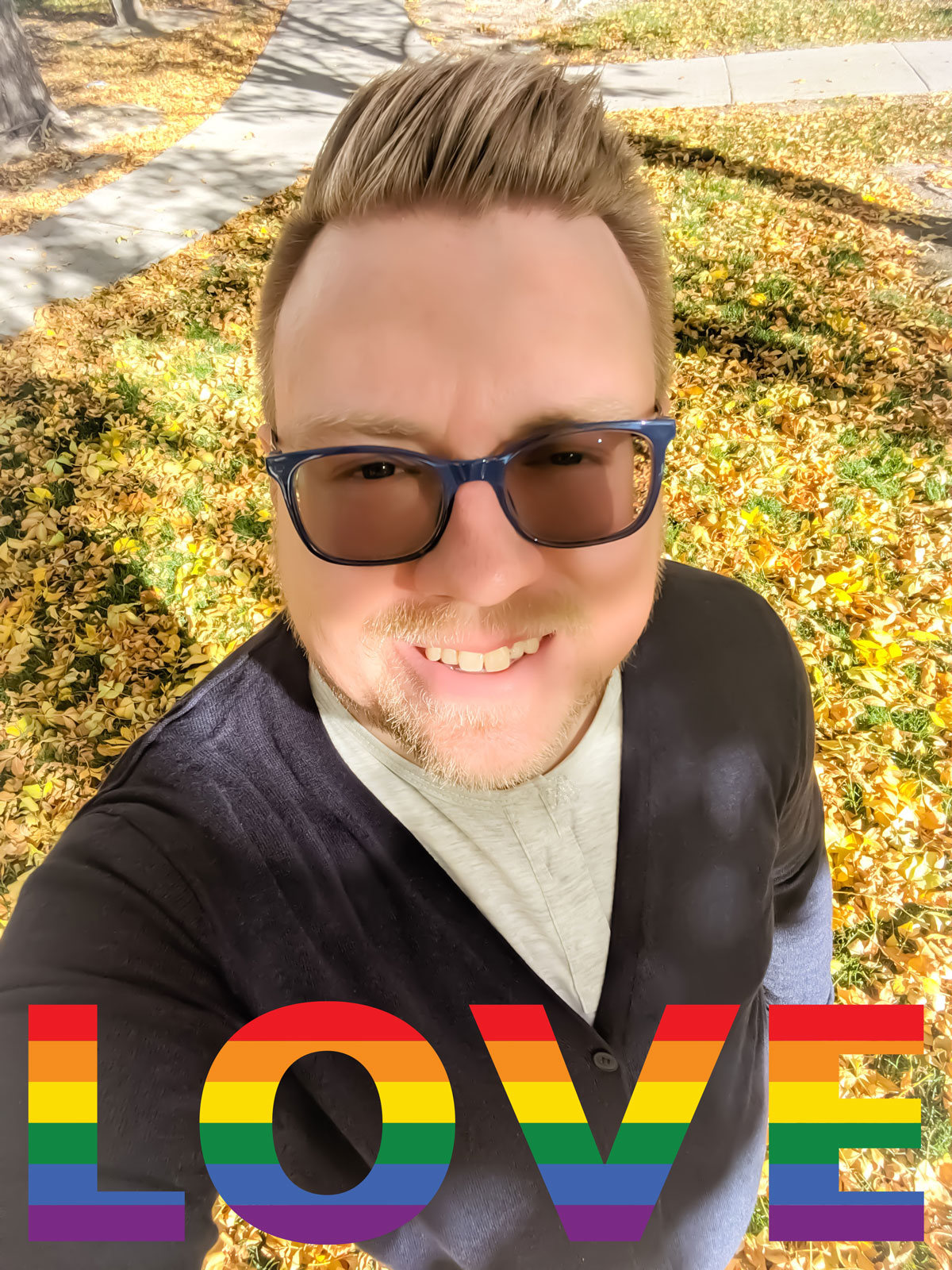 Dustin wearing sunglasses, standing in front of autumn leaves in the background